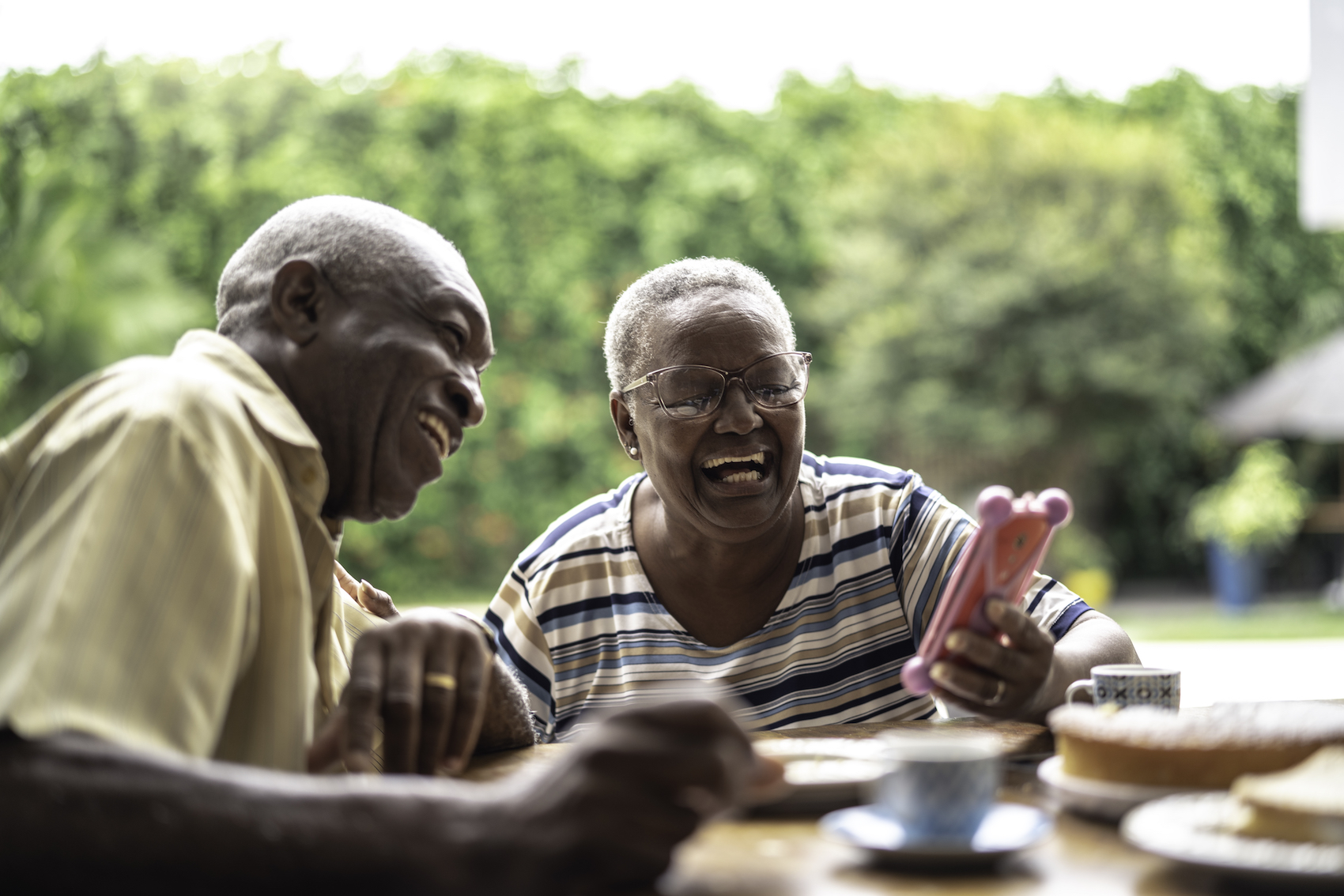 Older adults laughing together while looking at a smartphone